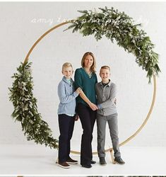 two children and an adult standing in front of a christmas wreath