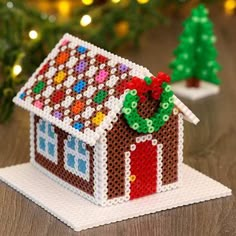 a small house made out of legos sitting on top of a table next to a christmas tree