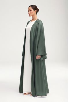 Transform any outfit into a statement with our Seema Flare Sleeve Open Abaya in Dark Forest. Its luxurious fabric boasts a subtle sheen, while the dramatic flare sleeves add a touch of artful elegance. Step out in style and sophistication with this exclusive piece. Model is 5'7" and is wearing size XS/58". Elegant Flowy Spring Abaya, Elegant Solid Color Abaya For Eid, Flowy Long Abaya For Eid, Elegant Long Sleeve Solid Color Kaftan, Elegant Silk Abaya With Long Sleeves, Elegant Long Sleeve Silk Abaya, Silk Long Abaya For Eid, Long Silk Abaya For Eid, Elegant Kaftan With Bell Sleeves