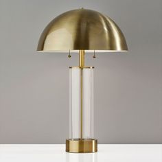 a brass and glass table lamp on a white surface with a gold dome light shade