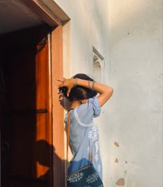 a woman standing in front of a door with her hand on her head