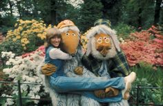 two people dressed as the muppets hugging each other in front of some flowers