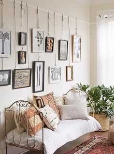 a bed with lots of pillows and pictures on the wall above it, along with a potted plant