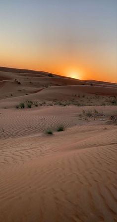 the sun is setting in the desert with sand dunes