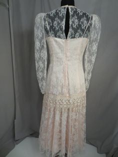 "Wonderful color and feminine styling on this vintage blush pink lace dress. It has a very pretty high neckline. The label is a mystery, only a paper tag sewn on says 11/12 and a code 5414 . Pink lining fabric has a sturdy feel and nice thickness. Lace overlay is sheer. Shape is very feminine, long sleeves with a drop waist. Waist has an extra layer of floral lace. Back zipper. Full skirt. Please convo me for any additional details or photos you would like. Marked size 11/12 but these sizes are Blush Pink Lace Dress, Lace Party Dress, Lace Party Dresses, Flapper Style, Flowing Skirt, Feminine Dress, Sheer Dress, Dress Vintage, Lace Overlay