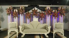 a living room filled with white furniture and flowers on the wall next to a window