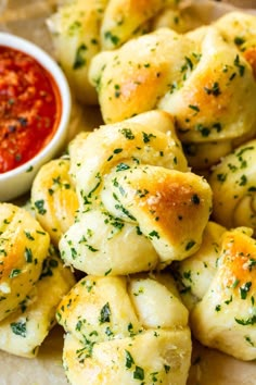 a white plate topped with dumplings next to a bowl of dipping sauce on top of a wooden table