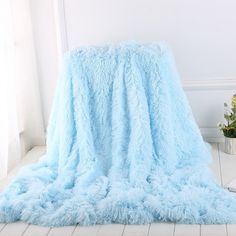 a light blue blanket sitting on top of a white floor next to a potted plant