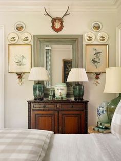 a bed room with a neatly made bed and two lamps on top of the dresser