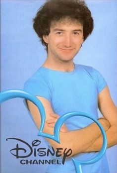 a man with his arms crossed in front of the disney channel logo, which is shaped like a heart