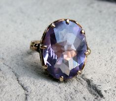 This is a stunning vintage ring with a  custom cut alexandrite stone.  It is 14k rose gold and has a beautiful design.  It holds a synthetic Alexandrite or color-change corundum.  It shows rich purple color and also has flashes of blue depending on the lighting.    Genuine alexandrite are very rare and expensive and synthetics like this are also sought after and were used in vintage jewelry.   The top measures 16.9mm x 13.5mm.  The stone is held in a pretty intricate crown with eight prongs. The Alexandrite Stone, Alexandrite Ring, Rich Purple, Right Hand Rings, Vintage Ring, Rose Gold Color, Selling Jewelry, Rings Statement, Olympia