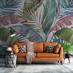 an orange leather couch in front of a wall with green palm leaves on the wall