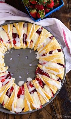 a cake that is sitting on a pan with strawberries in the background and one slice cut out