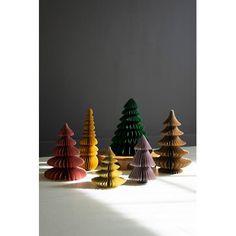 five brightly colored wooden christmas trees on a white surface