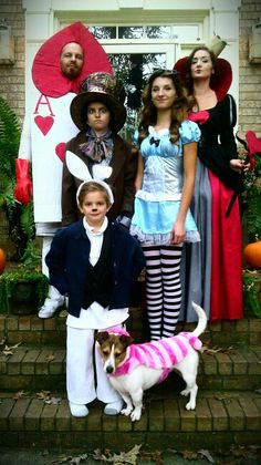 a group of people dressed up in costumes standing on steps with a dog and cat