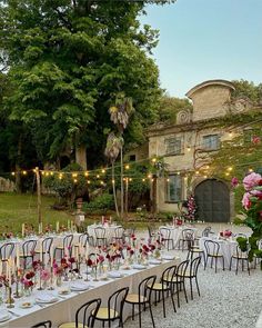 an outdoor dining area with tables and chairs set up for a formal dinner in the garden