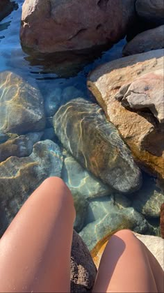 a person laying on rocks next to a body of water with their feet in the water