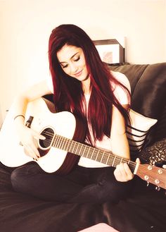 a woman sitting on a couch holding a guitar