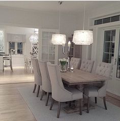 the dining room table is surrounded by white chairs and chandeliers with lights hanging from them