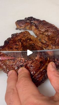 a person is cutting up some meat with a large knife on top of the steak