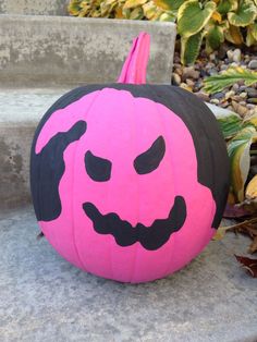 a pink and black pumpkin sitting on the ground