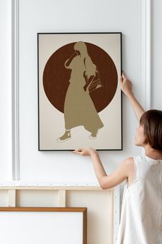 a woman is holding up a framed poster in the shape of a girl with a hat