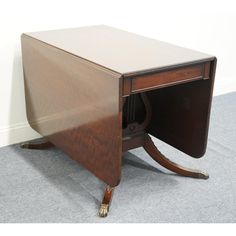 an antique desk with a wooden top and brass legs, on carpeted flooring