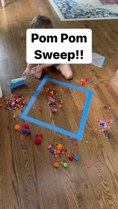 a child playing with pom pom sweep on the floor