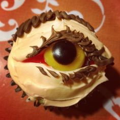 a cupcake with white frosting and chocolate decorations on it's face is decorated like an eye