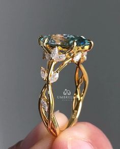 someone is holding up a fancy ring with an aqua topazte and white diamonds