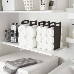 towels are stacked on top of the washer and dryer in this white laundry room