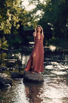 a woman is standing on a rock in the water