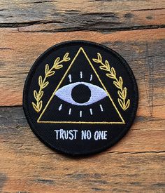 a patch that says trust no one with an eye in the center and laurel around it