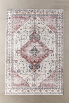 a red and white rug with an ornate design on the bottom, in front of a wall