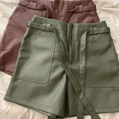 New Without Tags 2 Faux Leather Shorts. 1 Chocolate Color And 1 Olive Green Color. Faux Leather Bottoms For Day Out In Spring, Spring Leather Belted Bottoms, Trendy Faux Leather Bottoms For Day Out, Trendy Faux Leather Belted Bottoms, Trendy Belted Faux Leather Bottoms, Faux Leather Shorts With Pockets For Spring, Chic Faux Leather Shorts With Belt Loops, Trendy Leather Bottoms For Day Out, Chic Leather Shorts With Pockets