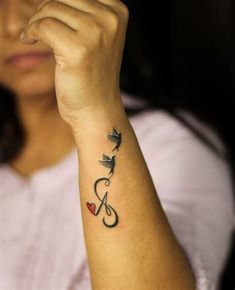 a woman with a tattoo on her arm holding a small bird and heart in the middle