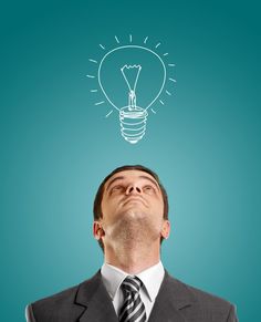 a man in a suit looking up at a light bulb above his head