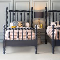 two twin sized beds with blue headboards and foot boards, one has a teddy bear on the bed