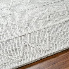 a white rug with an intricate design on the top and bottom, sitting on a wooden floor