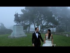 a bride and groom walking in front of a statue on a foggy day at the park