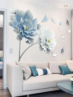 a living room with white furniture and blue flowers on the wall