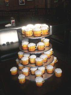 a tiered cake with cupcakes and beer mugs on the bottom layer