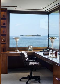 an office with a desk and chair in front of a large window overlooking the ocean