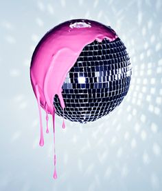 a disco ball with pink liquid dripping from it's side and on the floor