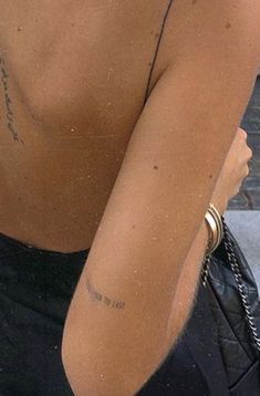 the back of a woman's body with tattoos on her left shoulder and right arm