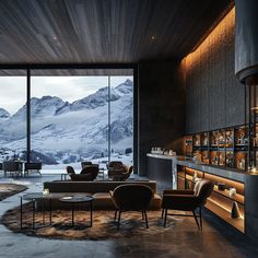 a living room filled with furniture next to a large glass window covered in snow capped mountains