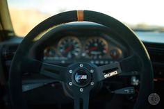 the steering wheel and dashboard of a car with speedometers on it's dash