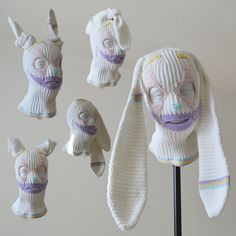 several knitted hats with faces and ears are hanging on a stand in front of a wall