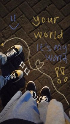 two people standing next to each other on a sidewalk with writing written on the ground