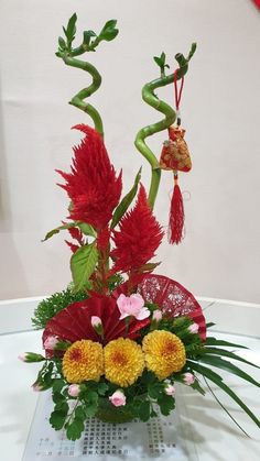 a vase filled with red and yellow flowers on top of a glass table next to a white wall